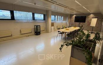 Spacious office space for rent in Utrecht Kanaleneiland at Bernadottelaan 13, featuring a large table, chairs, and a greenery-filled corner, ideal for collaborative work and meetings.