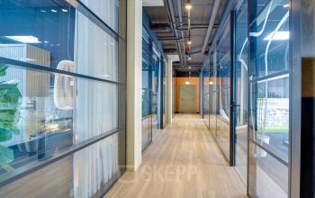 Modern hallway with glass partitions and wooden flooring in an office to rent at Europalaan 400, Utrecht Kanaleneiland. The design is sleek and contemporary, ideal for enhancing professional workspace environments.