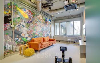 Vibrant office space at Europalaan 400, Utrecht Kanaleneiland featuring a lively mural, modern furniture, and natural light, perfect for office space rental.