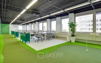 Modern office space in Utrecht Kanaleneiland at Europalaan 400, featuring open floorplan with several desks, ample natural light, and a unique indoor putting green; ideal for rent office space seekers.