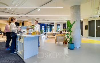 Modern workspace interior at Europalaan 500, Utrecht Kanaleneiland, featuring open floorplan, contemporary decor, and people engaging in business discussions, ideal for office space rental with collaborative areas.