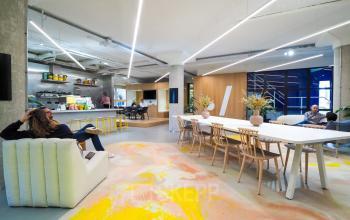 Modern office space rental at Europalaan 500, Utrecht Kanaleneiland, displaying an inviting communal area with vibrant decor, comfortable seating, and a collaborative atmosphere enhanced by people engaged in discussion and work activities.