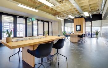Modern office with open floor plan at Europalaan 101, Utrecht Kanaleneiland, featuring sleek wooden tables, contemporary seating, and natural light. Ideal for office space rental with collaborative workspaces.