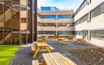 Courtyard view of the office building at Europalaan 93 in Utrecht Kanaleneiland, featuring outdoor seating and modern architecture, ideal for refreshing breaks. Perfect office space rental opportunity.