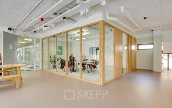 Modern office interior at Europalaan 93, Utrecht Kanaleneiland, featuring glass-walled meeting rooms and open workspaces, ideal for office space rental. The contemporary layout promotes productivity.