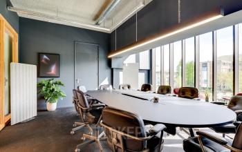 Contemporary conference room with large oval table and cushioned swivel chairs at Europalaan 93, Utrecht Kanaleneiland. Bright windows overlook the cityscape, ideal for office space rental.