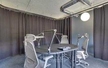 Modern podcast studio rental at Europalaan 93, Utrecht Kanaleneiland, featuring a round table with professional microphones and gray ergonomic chairs, ideal for creative business setups.