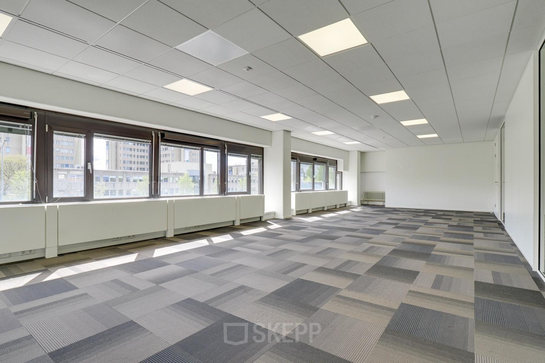 Bright office space rental at Europalaan 93 in Utrecht Kanaleneiland with large windows and patterned carpet, offering a spacious and versatile layout ideal for various business activities.