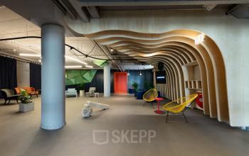 Modern open floor plan office space rental at Europalaan 100, Utrecht Kanaleneiland, featuring unique architectural accents, comfortable seating, and vibrant decor, ideal for creative work environments.