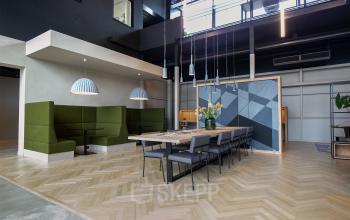 Modern office space rental at Atoomweg 63, Utrecht Lage Weide, with stylish green seating and a large meeting table under elegant lampshades.