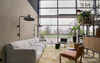 A modern, furnished office lounge space at Atoomweg 63, Utrecht Lage Weide, featuring comfortable seating, stylish decor, and large windows providing natural light. Ideal for rent office space seekers.