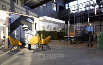 Modern office space at Atoomweg 63, Utrecht Lage Weide, featuring stylish furnishings and a professional ambiance. A person is making a phone call in the workspace area, suitable for office space rental.