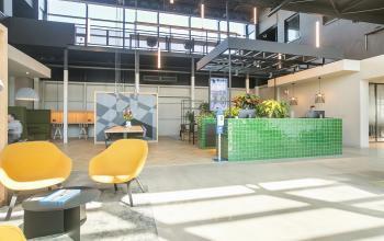 Bright office interior at Atoomweg 63, Utrecht Lage Weide, showcasing furnished open floorplan with inviting seating area and green reception desk, ideal for office space rental.