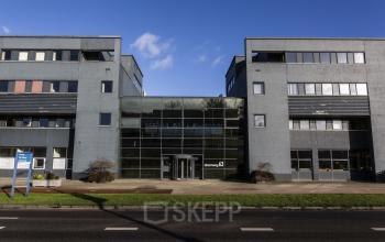 Exterior view of Atoomweg 63, located in Utrecht Lage Weide, featuring a modern office building with a glass entrance, available for office space rental.