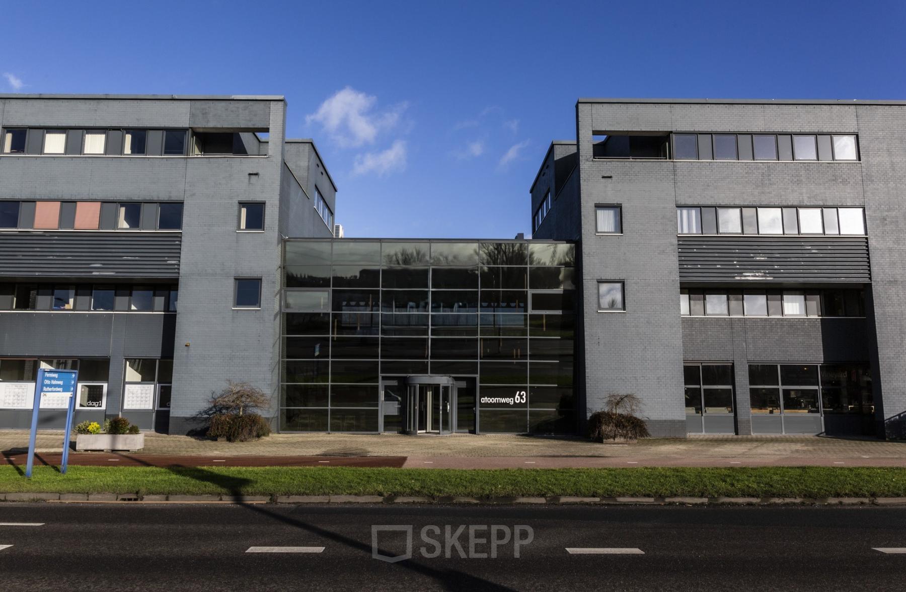 Exterior view of Atoomweg 63, located in Utrecht Lage Weide, featuring a modern office building with a glass entrance, available for office space rental.
