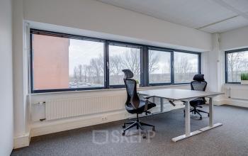 Bright office space for rent at Zonnebaan 45, Utrecht Lage Weide, featuring large windows and modern furnishings including two chairs and a desk.