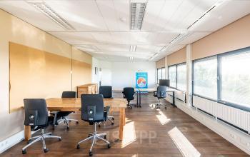 Bright office space at Zonnebaan 45 in Utrecht Lage Weide featuring large windows, wooden flooring, and ergonomic chairs around wooden desks, ideal for office space rental.