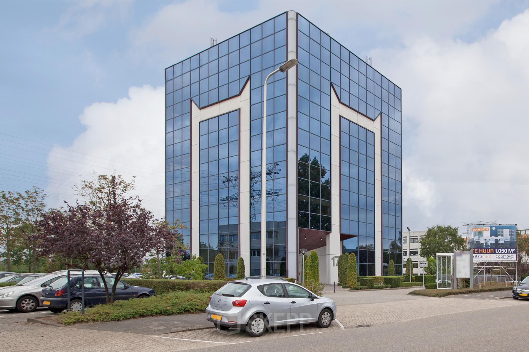 Modern office building at Savannahweg 17, Utrecht Lage Weide, reflecting the sky on its glass facade, with parking spaces in the foreground.