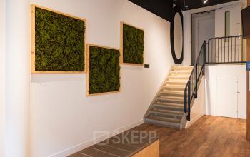 Entrance area of the office at Middenburcht 136, Utrecht Leidsche Rijn, featuring greenery on the walls and a staircase leading to upper floors.