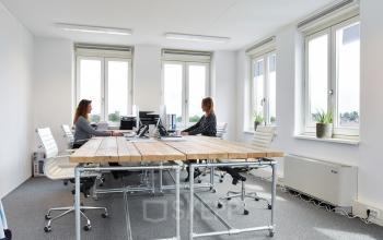 Bright office space rental at Middenburcht 136, Utrecht Leidsche Rijn with large windows, conference table, and two professionals working.