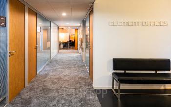 Hallway at Middenburcht 136, Utrecht Leidsche Rijn, leading to various office spaces available for rent, furnished with a bench and modern lighting.