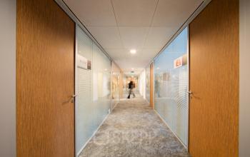 Modern hallway in an office at Middenburcht 136, Utrecht Leidsche Rijn, featuring glass doors and subtle lighting.