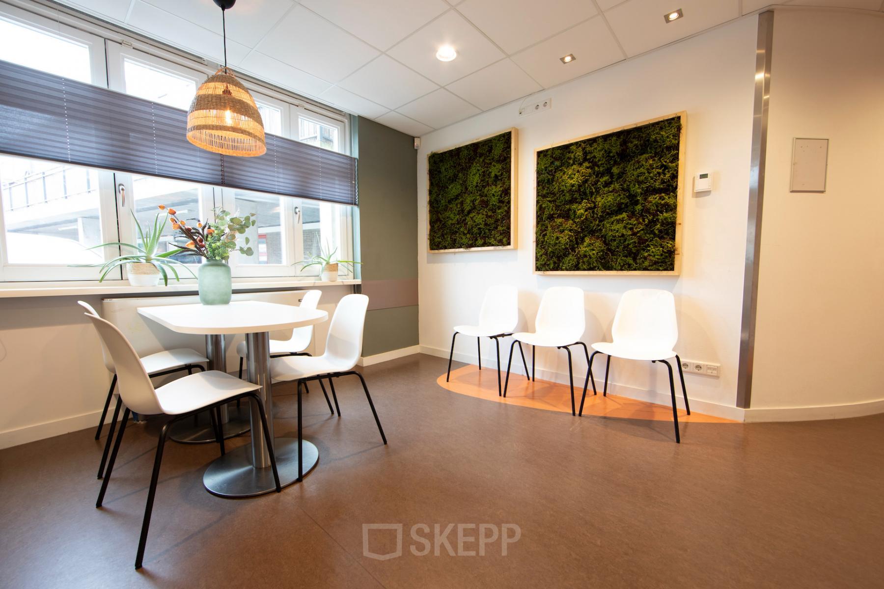 Bright, modern workspace at Middenburcht 136, Utrecht Leidsche Rijn, featuring a round table with chairs, green wall decor, and large windows.