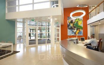 Spacious modern reception area at Zwarte Woud 2 in Utrecht Lunetten, featuring a large desk, colorful wall art, and natural light from large windows.