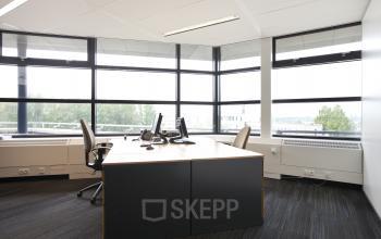Bright office space with large windows, modern furniture, and computer workstations at Zwarte Woud 2, Utrecht Lunetten, ideal for office space rental.