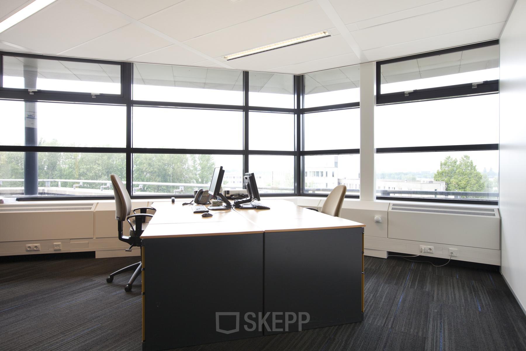 Bright office space with large windows, modern furniture, and computer workstations at Zwarte Woud 2, Utrecht Lunetten, ideal for office space rental.