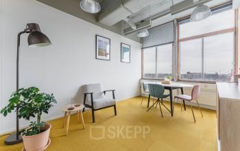 Bright office space with modern decor at Goeman Borgesiuslaan 77, Utrecht North, featuring a table with chairs, a potted plant, and framed art. Ideal for office space rental.