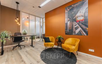Modern office space rental at Goeman Borgesiuslaan 77 in Utrecht North, featuring stylish seating area with yellow chairs, black rug, and contemporary wall art.