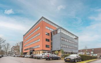 Exterior view of the office building at Goeman Borgesiuslaan 77, Utrecht North, featuring a modern and colorful design with ample parking spaces. Ideal for those seeking office space rental in a vibrant location.
