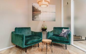 Cozy office lounge area with stylish green armchairs and a small round table, ideal for informal meetings or breaks at Goeman Borgesiuslaan 77, Utrecht North. Perfect spot for office space rental.