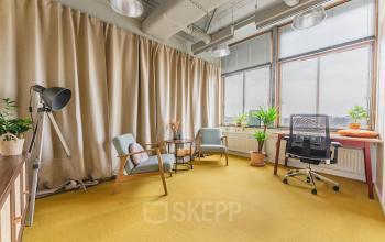 Spacious office to rent at Goeman Borgesiuslaan 77, Utrecht North, featuring comfortable seating, a desk with chair, large windows, and vibrant plants, creating an inviting work environment.