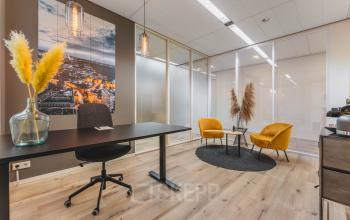 Modern office space rental in Utrecht North featuring stylish furnishings, large glass partitions, and warm lighting for a productive work environment.