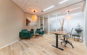 Modern office space for rent at Goeman Borgesiuslaan 77 in Utrecht North with stylish furnishings, two green chairs, a desk, and vibrant decor enhancing a professional atmosphere.