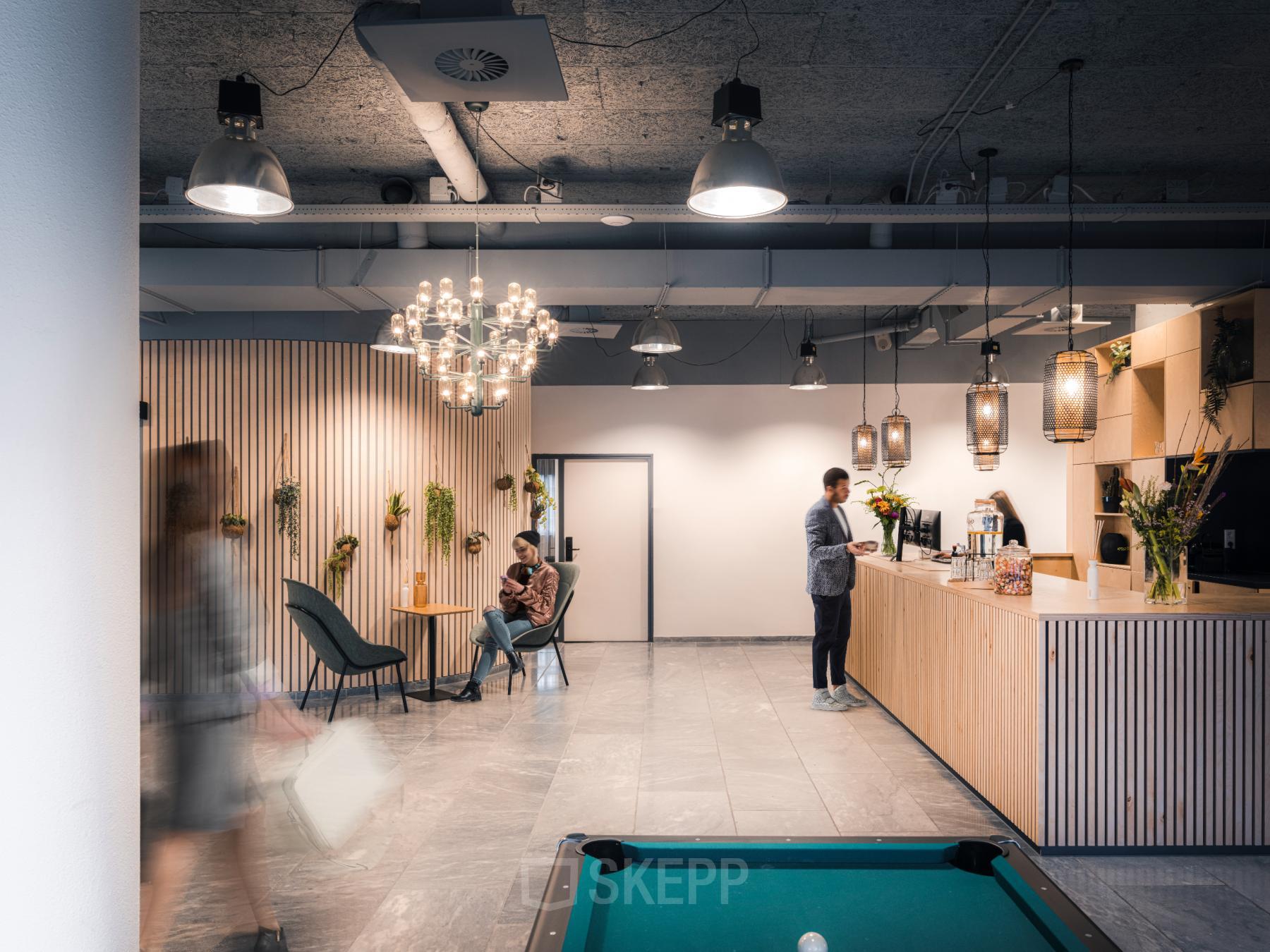 Modern office lounge at Goeman Borgesiuslaan 77, Utrecht North. Featuring comfortable seating, a coffee bar, and decorative lighting, ideal for office space rental.