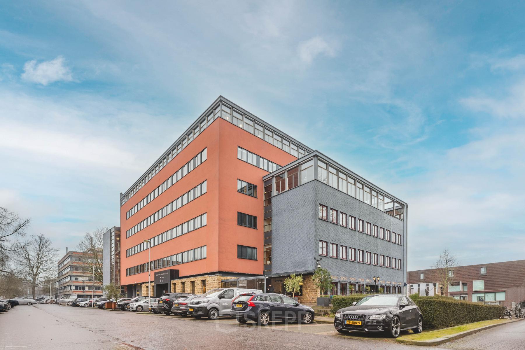 Exterior view of the office building at Goeman Borgesiuslaan 77, Utrecht North, featuring a modern and colorful design with ample parking spaces. Ideal for those seeking office space rental in a vibrant location.
