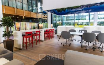 Modern office space rental in Utrecht Papendorp with sleek furnishings, featuring red bar stools and comfortable meeting chairs, perfect for work and collaboration.