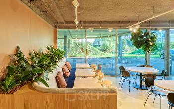 Modern office space rental at Van Deventerlaan 30-40, Utrecht Papendorp, featuring stylish seating, greenery, and bright natural lighting through large windows.