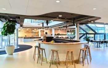 Modern open floor plan with a circular bar, stools, and natural light at Van Deventerlaan 30-40 in Utrecht Papendorp for office space rental.