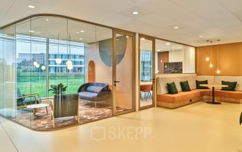 Modern and stylish office lounge with seating and a glass-enclosed meeting area at Van Deventerlaan 30-40, offering vibrant office space rental options in Utrecht Papendorp.