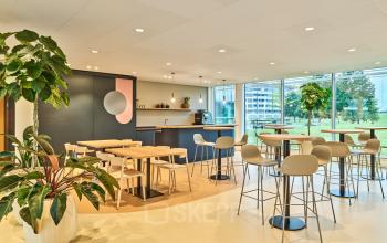A modern, furnished office lounge with wooden tables and chairs at Van Deventerlaan 30-40, Utrecht Papendorp, ideal for office space rental.