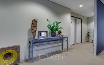 Modern and welcoming entrance hallway at the office space rental at Orteliuslaan 850, Utrecht Papendorp, featuring plants and artistic decor.