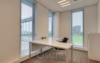 Well-lit office space rental at Orteliuslaan 850, Utrecht Papendorp, with a clean desk and chair by a large window offering a view.