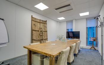 Contemporary office space rental at Orteliuslaan 850, Utrecht Papendorp with wooden table, large TV, and modern decor.