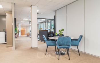 Modern office space rental at Orteliuslaan 850 in Utrecht Papendorp featuring a bright interior with a round table and blue chairs.