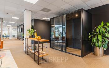 Spacious office with modern furnishings at Orteliuslaan 850, Utrecht Papendorp, ideal for office space rental, featuring a sleek meeting booth and greenery accents.