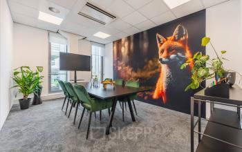 Bright office space for rent in Utrecht Papendorp featuring a large fox mural, conference table, chairs, and plants, offering a modern setup for meetings.